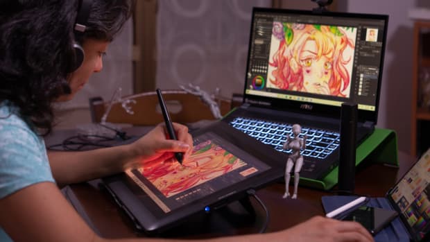 Young woman creating digital art on a drawing tablet and laptop.