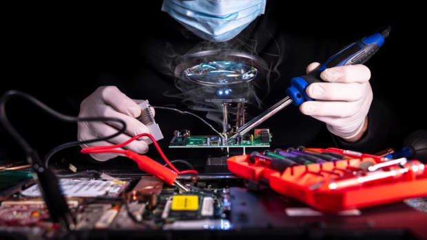 A person soldering a computer circuit board.