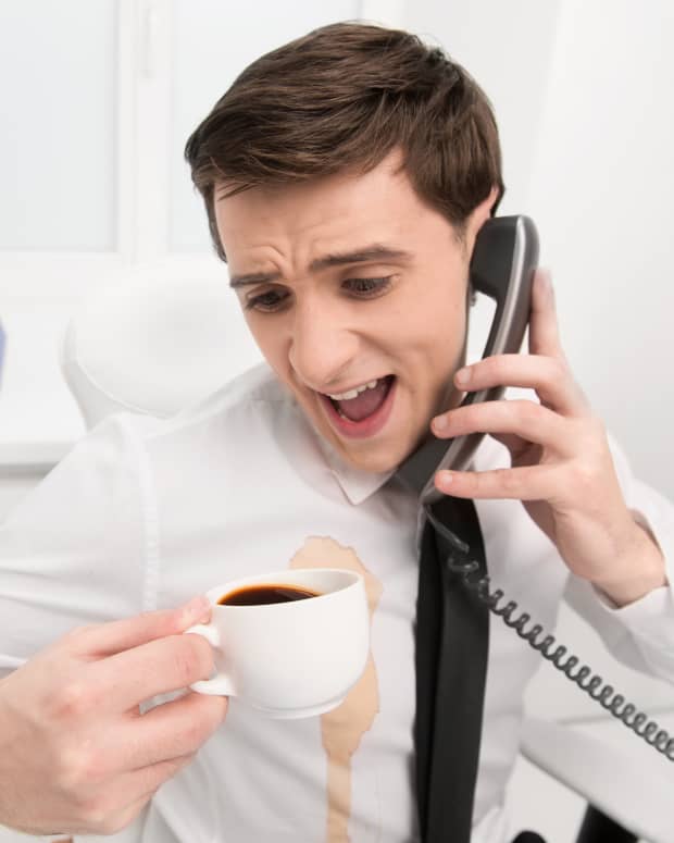 Man in dress shirt spills coffee while on phone