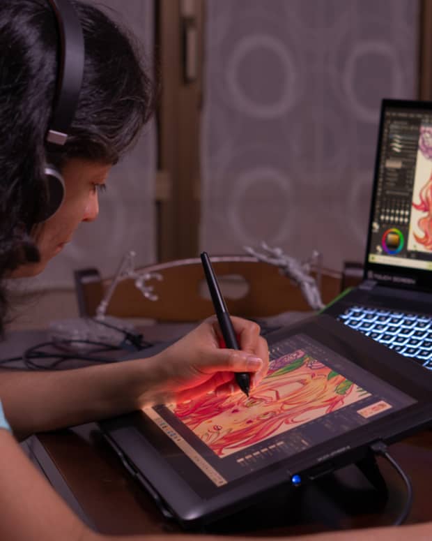 Young woman creating digital art on a drawing tablet and laptop.