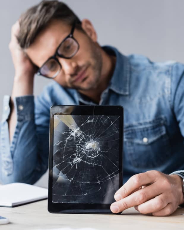 Man holding a tablet with a broken screen.