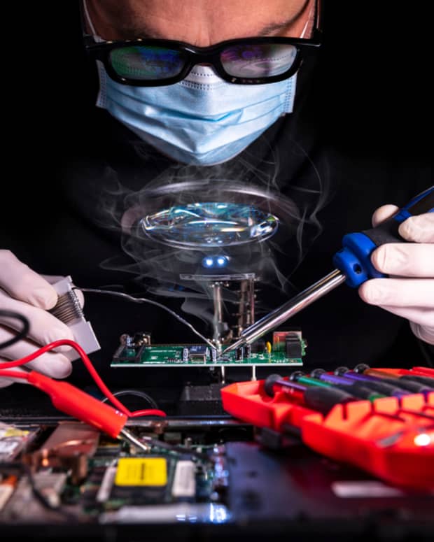 A person soldering a computer circuit board.